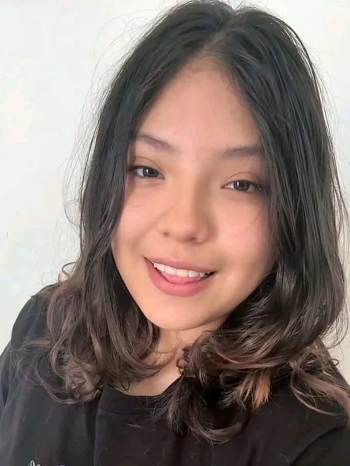 Smiling woman with wavy brown hair looking into her camera